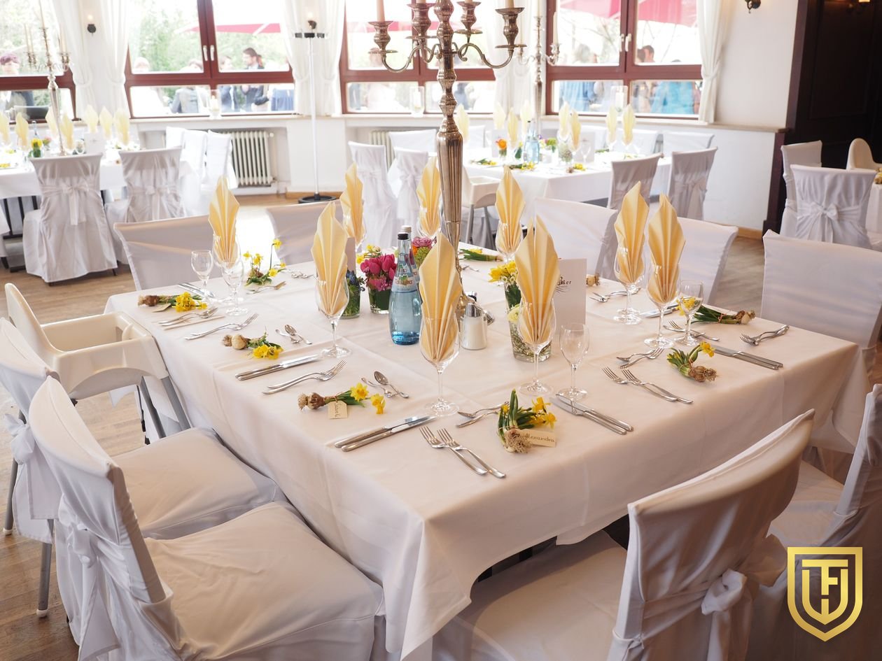 Banquet room set with linen-draped tables, folded napkins and chair covers before service